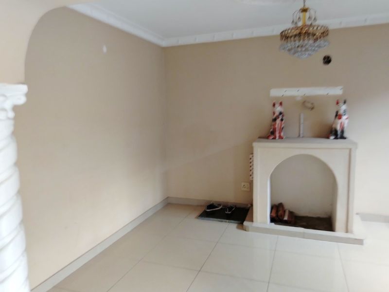 An empty living room featuring a built-in fireplace, decorative column, tiled flooring, and classic ceiling cornice detailing.