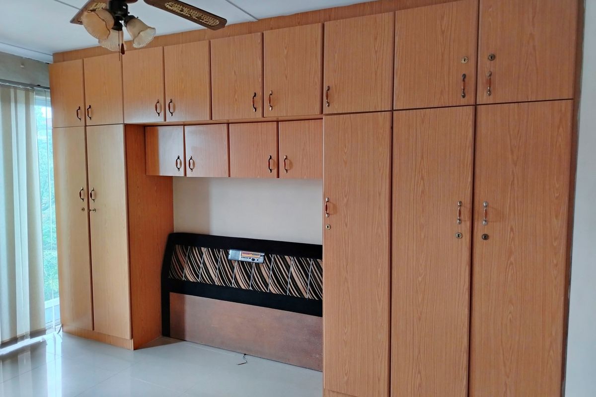 Bedroom featuring extensive built-in wooden cabinetry and wardrobes, a ceiling fan, and vertical window blinds.