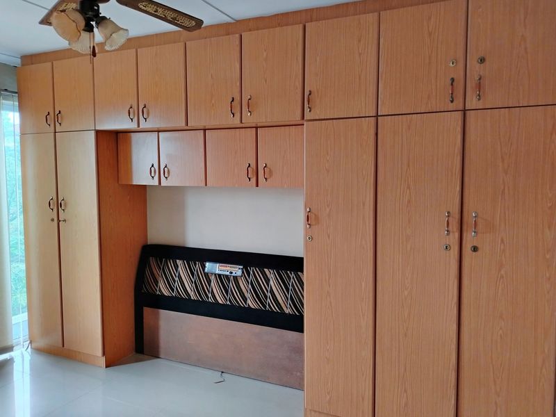 Bedroom featuring extensive built-in wooden cabinetry and wardrobes, a ceiling fan, and vertical window blinds.