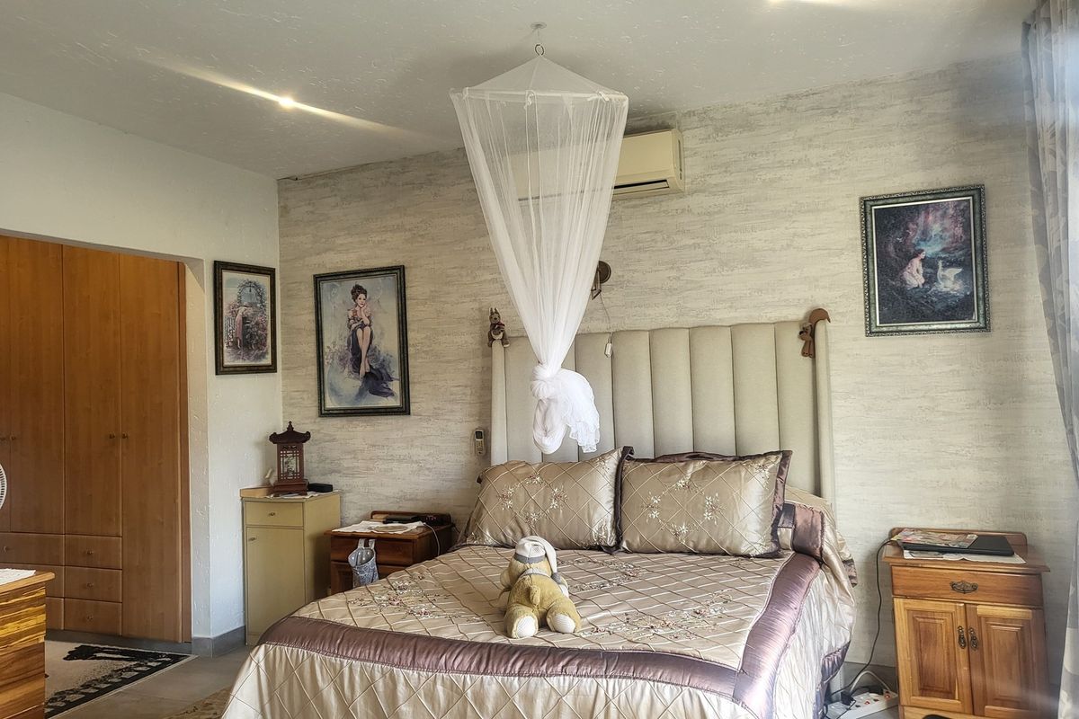 A bedroom featuring built-in wooden cabinetry, a wall-mounted air conditioning unit, and textured wallpaper.