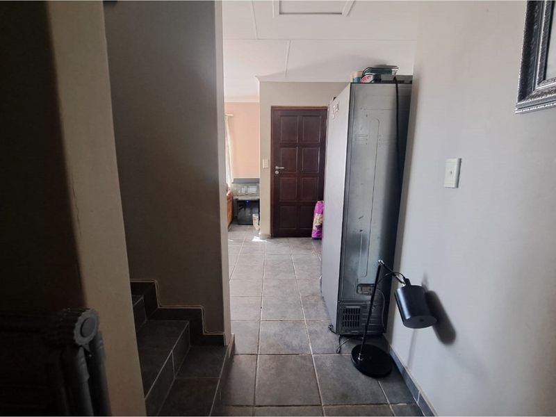 A tiled hallway area providing access to adjacent rooms, featuring a staircase and a solid timber entrance door.