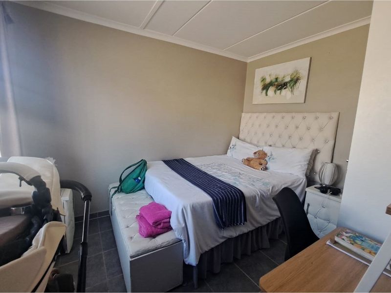 A functional bedroom featuring tiled flooring and a neutral color palette, providing a comfortable and practical living space.