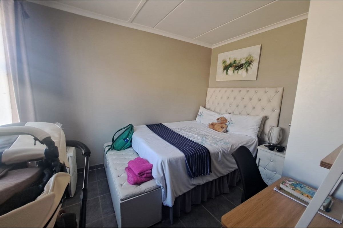 A functional bedroom featuring tiled flooring and a neutral color palette, providing a comfortable and practical living space.
