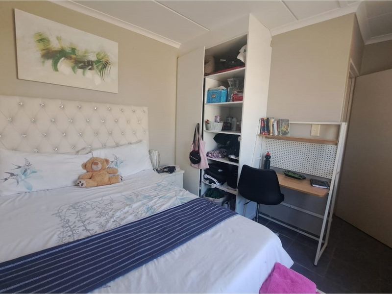 A functional bedroom featuring a built-in wardrobe and tiled flooring, providing a practical living space.