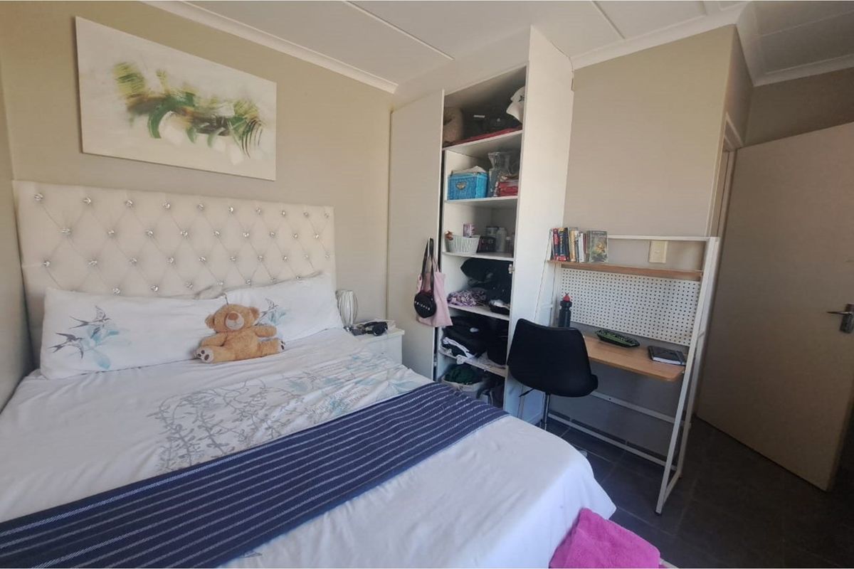 A functional bedroom featuring a built-in wardrobe and tiled flooring, providing a practical living space.