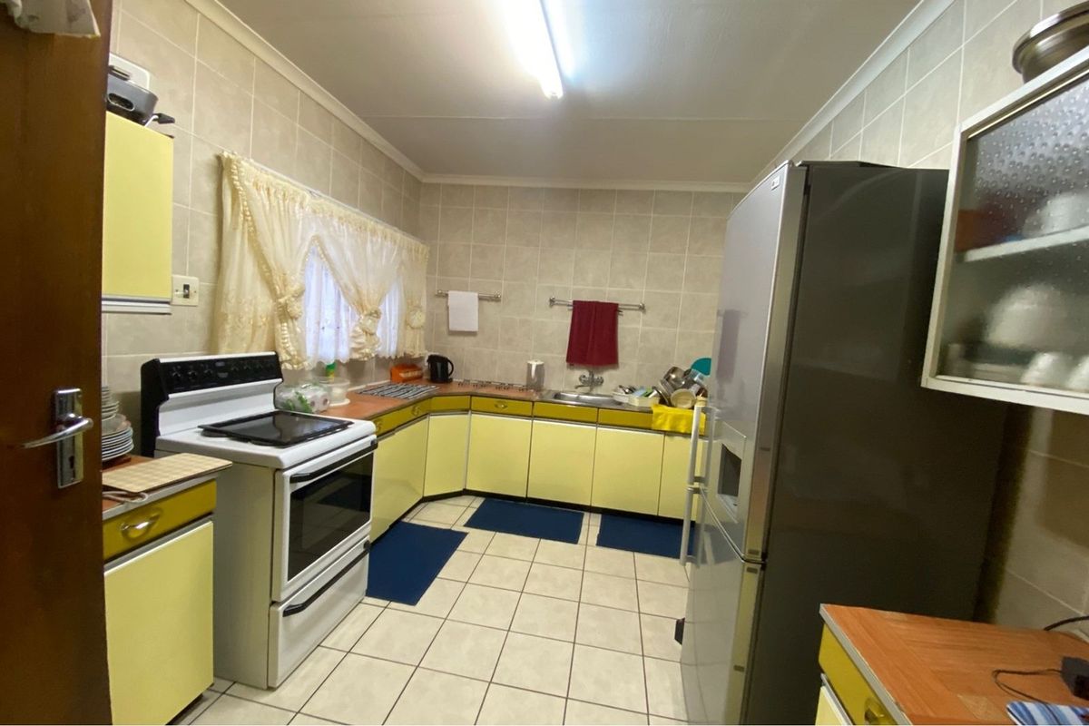 A functional kitchen featuring tiled walls and flooring, built-in cabinetry, and a freestanding stove, offering a practical layout for daily meal preparation.