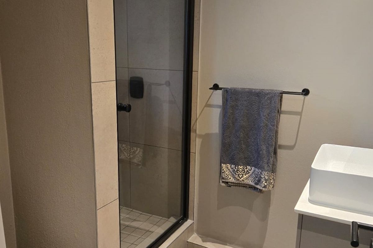 A modern bathroom featuring a glass-enclosed shower with tiled walls and a contemporary vessel sink vanity.