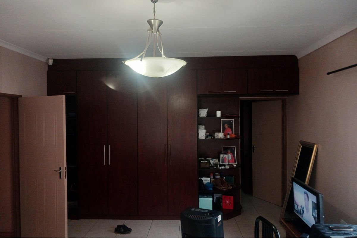 Bedroom featuring extensive built-in dark wood cabinetry with overhead storage and tiled flooring.