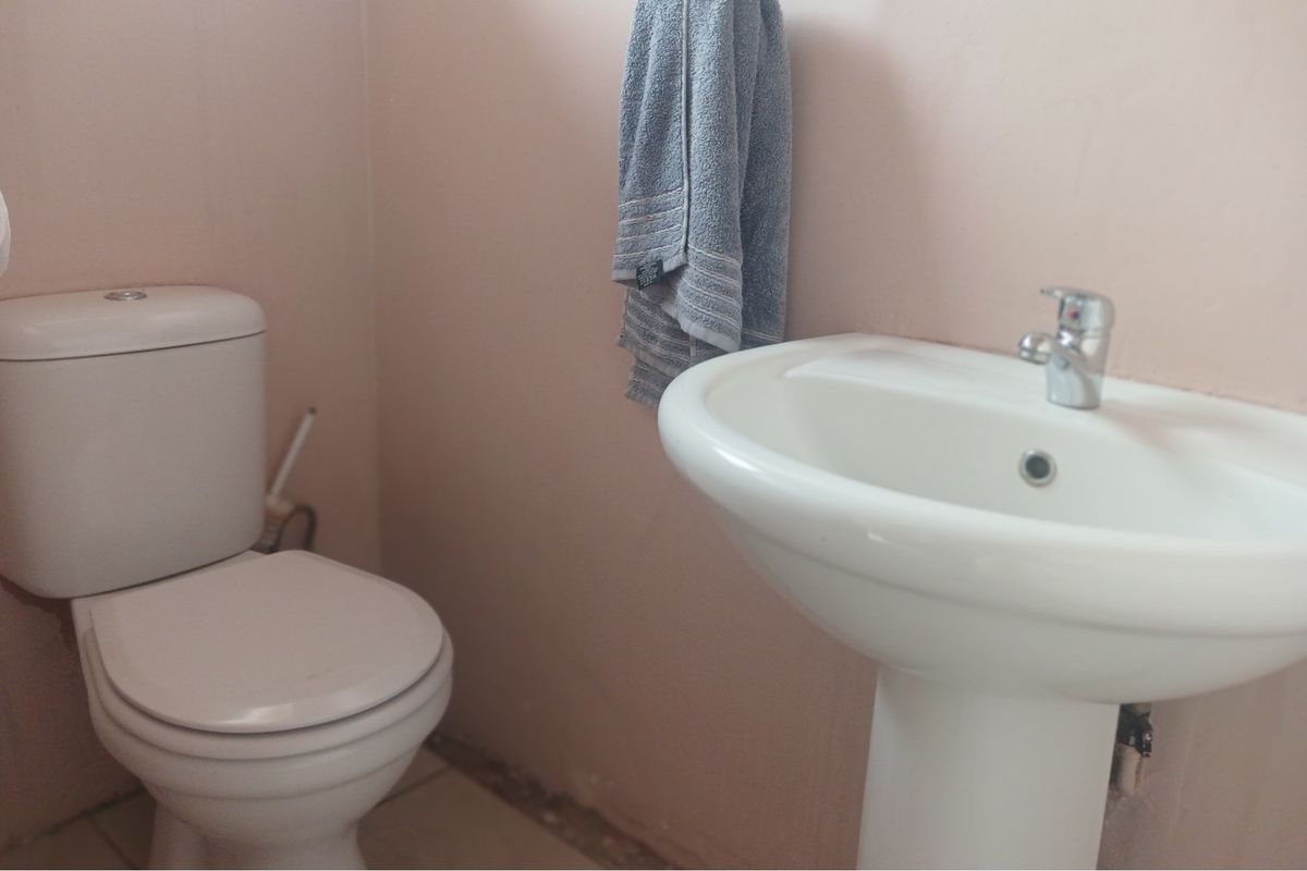 A compact bathroom featuring a white pedestal basin and a standard close-coupled toilet suite.