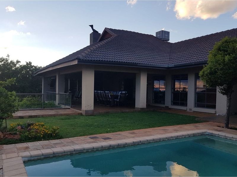 Rear view of the house featuring a covered patio, swimming pool, and landscaped garden area.