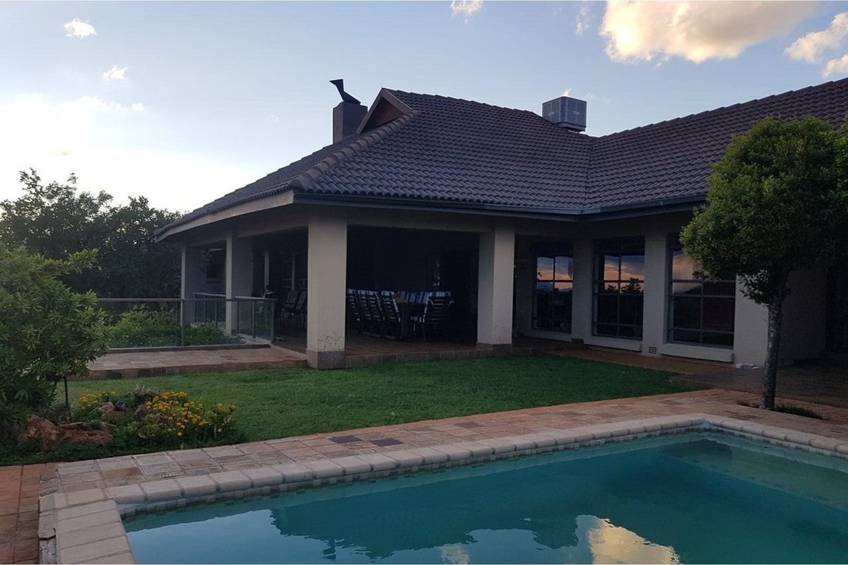 Rear view of the house featuring a covered patio, swimming pool, and landscaped garden area.
