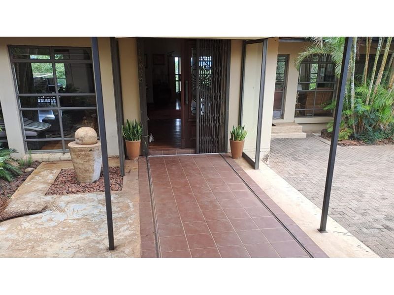 Covered front entrance featuring tiled walkway, security gate, and integrated water feature, providing a welcoming approach to the main residence.