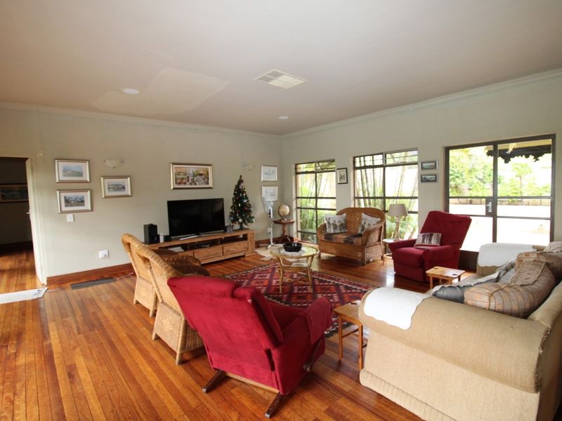 Spacious living room featuring polished timber flooring, large windows, and sliding glass doors providing natural light and access to the outdoor area.