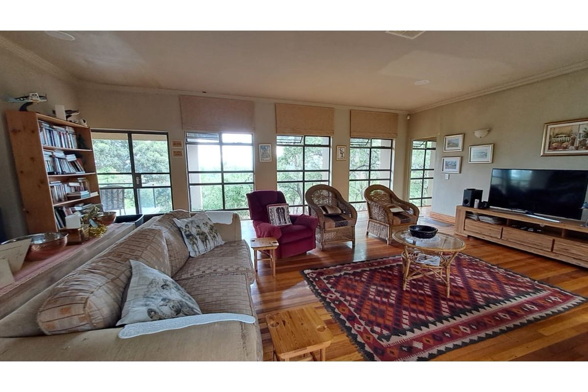 Spacious living room featuring polished timber flooring, large windows with natural light, and a neutral color palette.