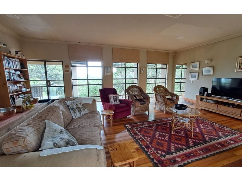 Spacious living room featuring polished timber flooring, large windows with natural light, and a neutral color palette.