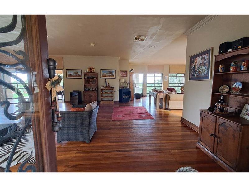 Spacious open-plan living area featuring polished timber flooring, large windows providing natural light, and a seamless flow between connected living spaces.