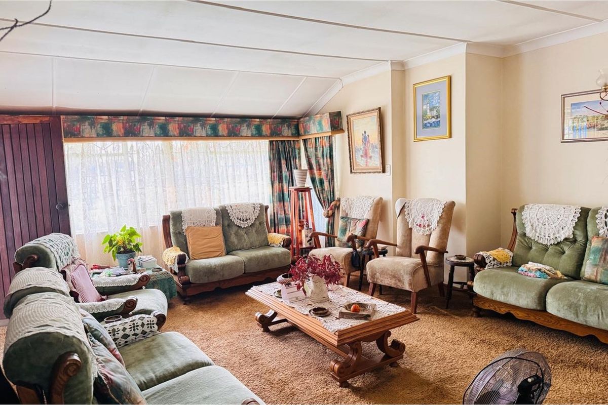 A spacious living room featuring large windows, carpeted flooring, and a traditional layout, offering a comfortable space for relaxation.