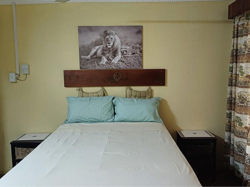A bedroom featuring a wooden headboard, ceiling fan, and curtain rail, with yellow painted walls.