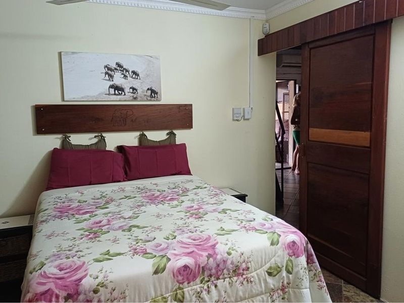 A bedroom featuring a ceiling fan, crown molding, and a sliding wooden door leading to an adjacent space.