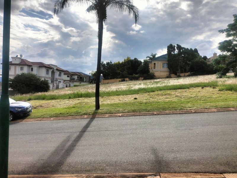 A vacant residential plot situated in a developed neighborhood, featuring established grass and surrounding residential properties.