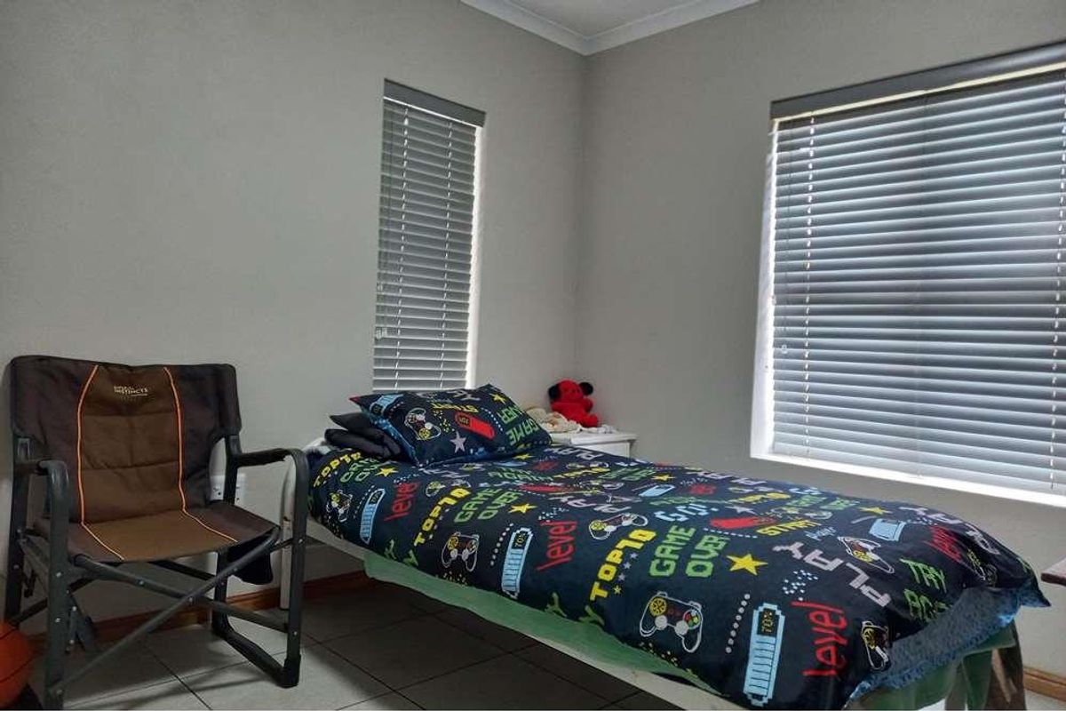 A bedroom featuring tiled flooring, neutral wall paint, and two windows fitted with horizontal blinds.