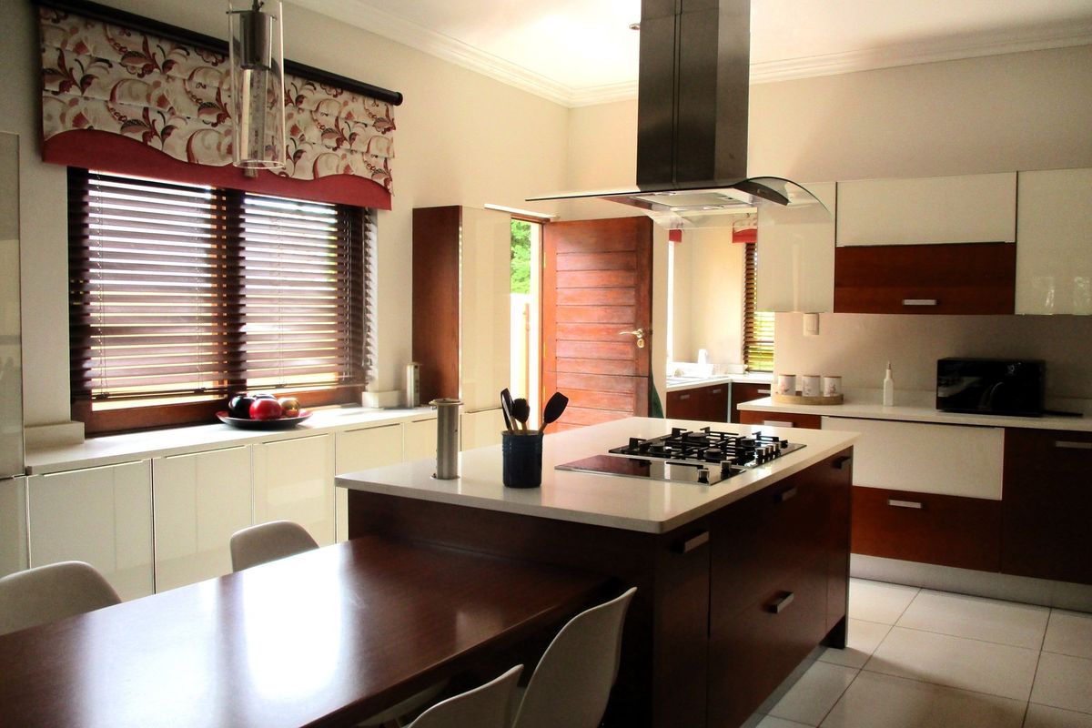 Modern kitchen featuring a central island with a built-in gas hob, stainless steel extractor fan, and sleek cabinetry with stone countertops.