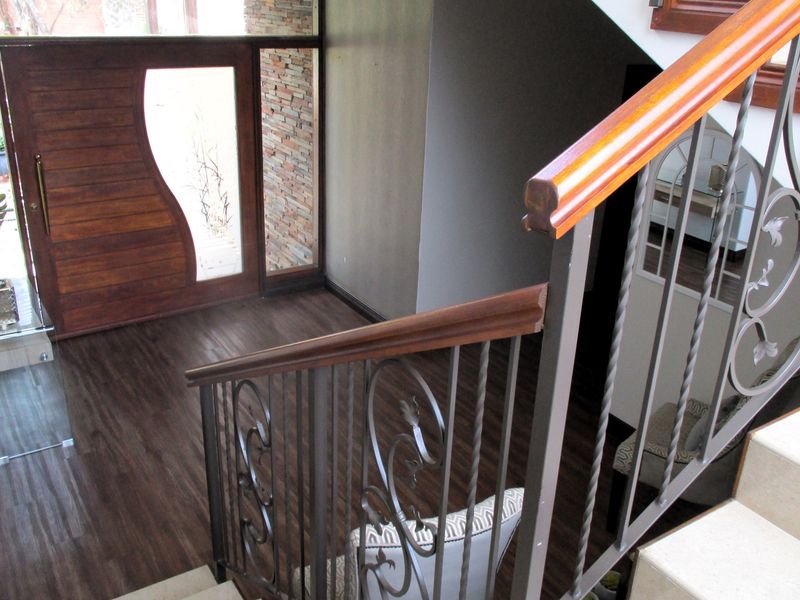 Entrance foyer featuring a custom timber front door with glass inlay, stone feature wall, and a staircase with decorative wrought iron balustrades.