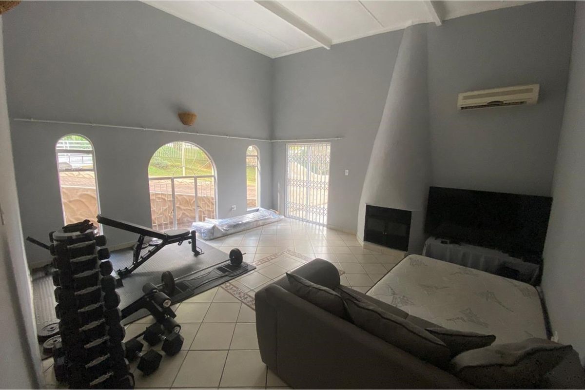 Spacious living area featuring high vaulted ceilings, tiled flooring, a unique conical fireplace, and arched windows providing natural light.