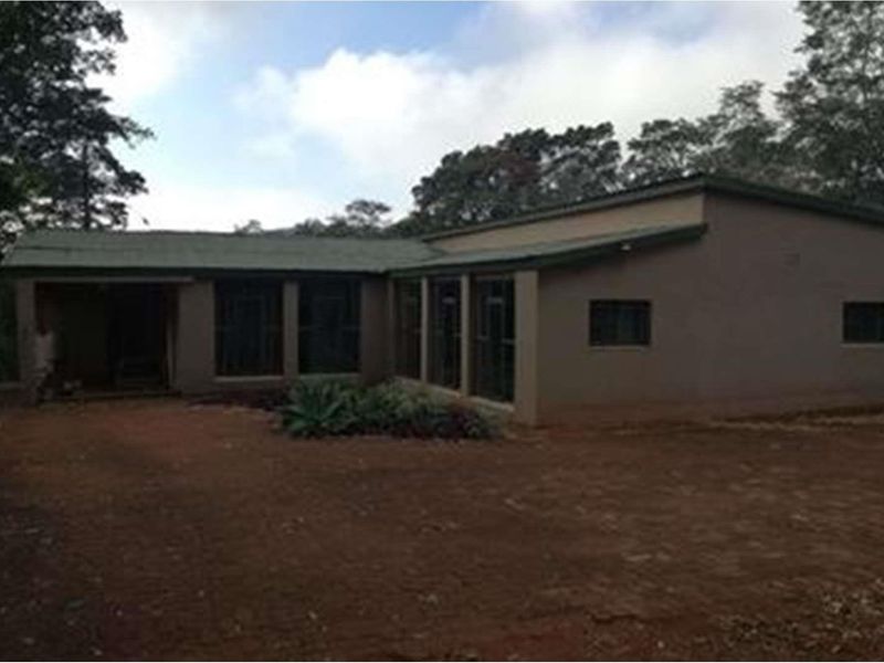 Exterior view of a single-story farm dwelling featuring a simple roofline and large windows, set on a rural plot.