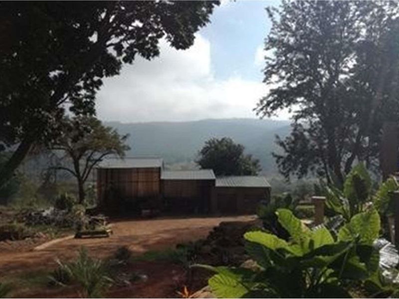 A scenic view of the farm property featuring outbuildings set against a backdrop of rolling hills and mature trees.