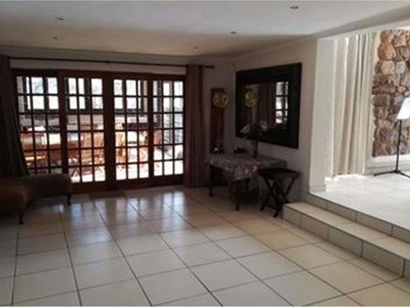 Spacious living area featuring tiled flooring, recessed lighting, and large wooden-framed glass sliding doors leading to an outdoor patio space.