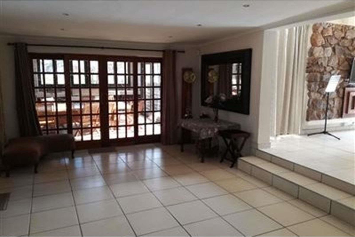 Spacious living area featuring tiled flooring, recessed lighting, and large wooden-framed glass sliding doors leading to an outdoor patio space.