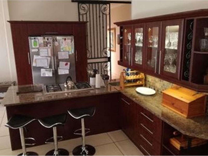 A kitchen featuring dark wood cabinetry, granite countertops, a built-in gas hob, and a decorative security gate leading to the adjacent space.