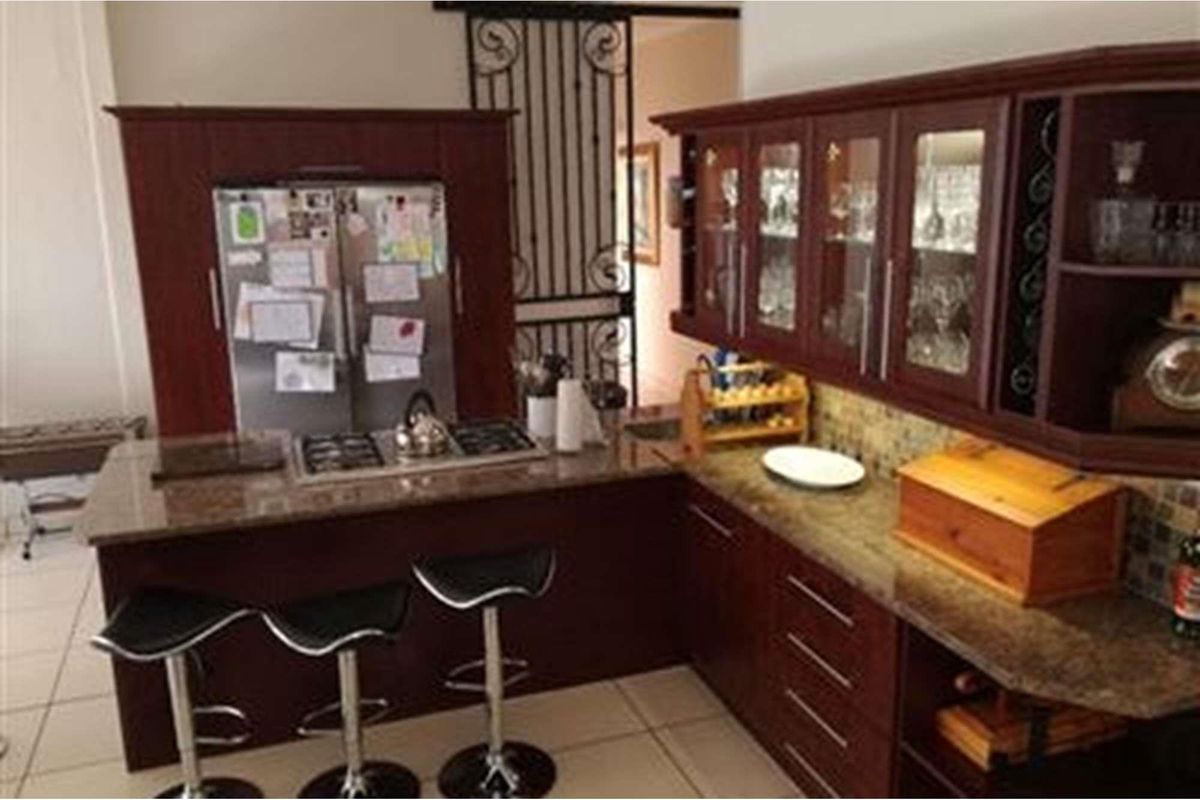 A kitchen featuring dark wood cabinetry, granite countertops, a built-in gas hob, and a decorative security gate leading to the adjacent space.