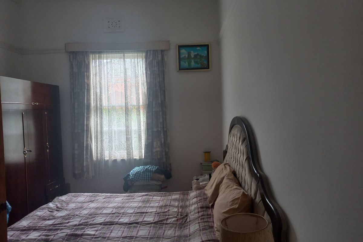 A bedroom featuring a window with curtains and a picture rail, providing a functional and lived-in space.