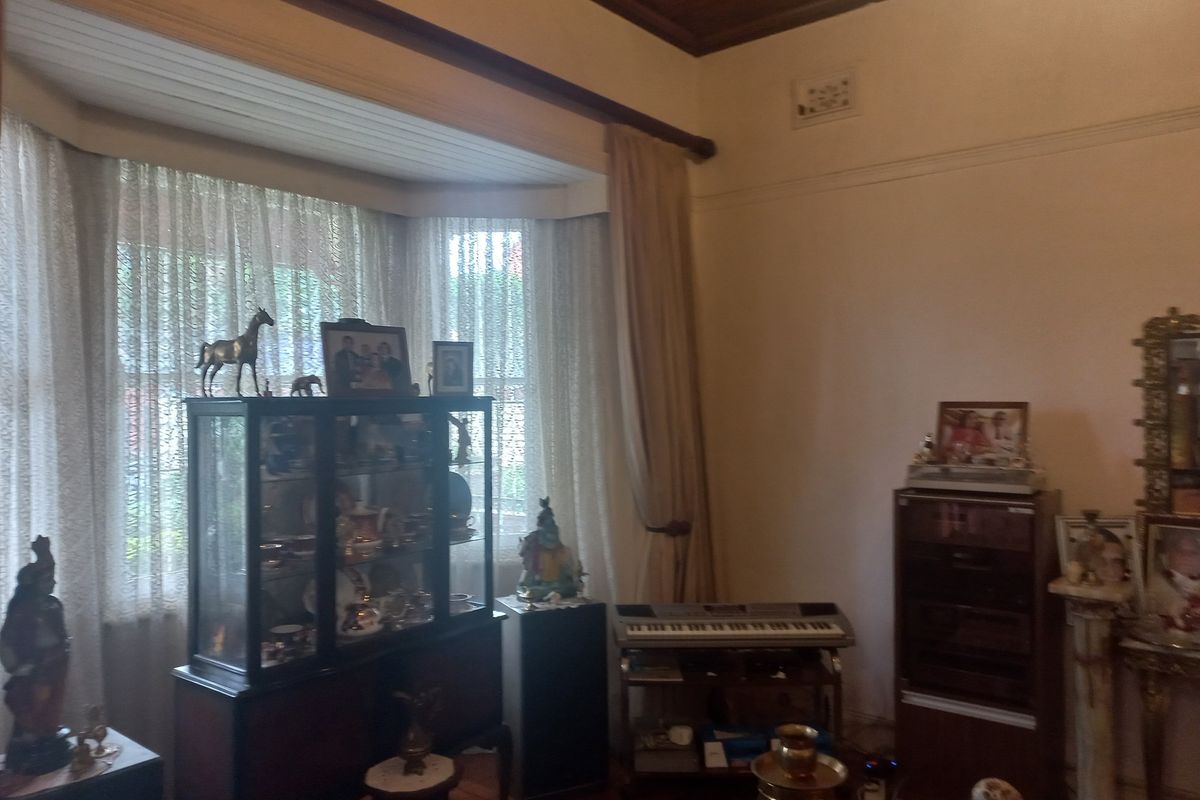 A living room featuring a large bay window with timber-framed ceiling details and traditional picture rails.