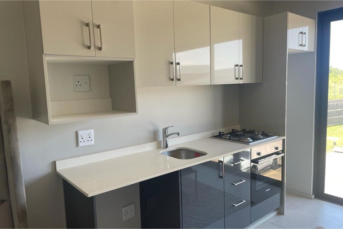Modern kitchen featuring high-gloss cabinetry, stone countertops, a built-in gas hob, and an integrated oven, with direct access to the outdoor area.