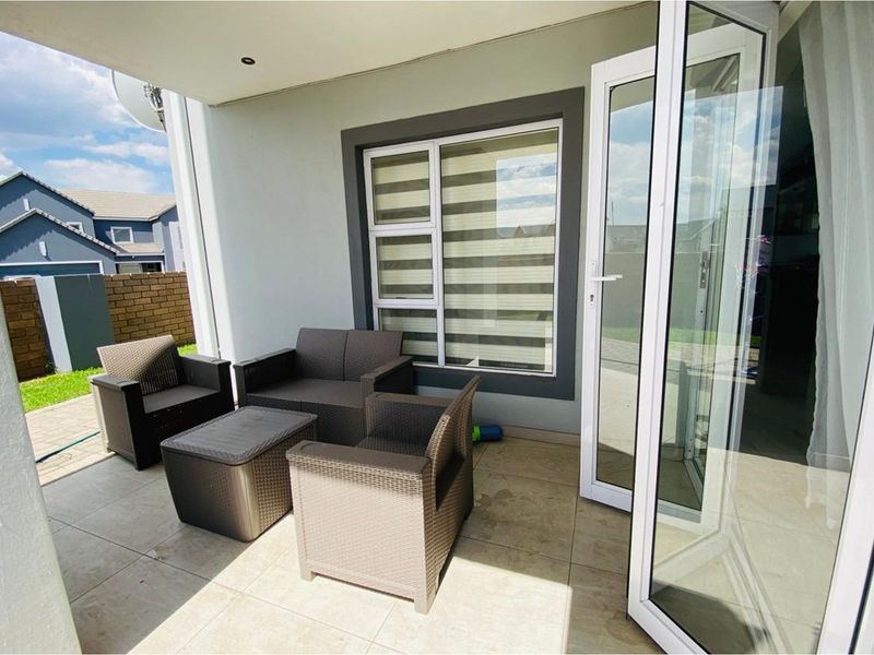 A covered patio area featuring tiled flooring and large glass stacker doors providing seamless access to the interior living space.