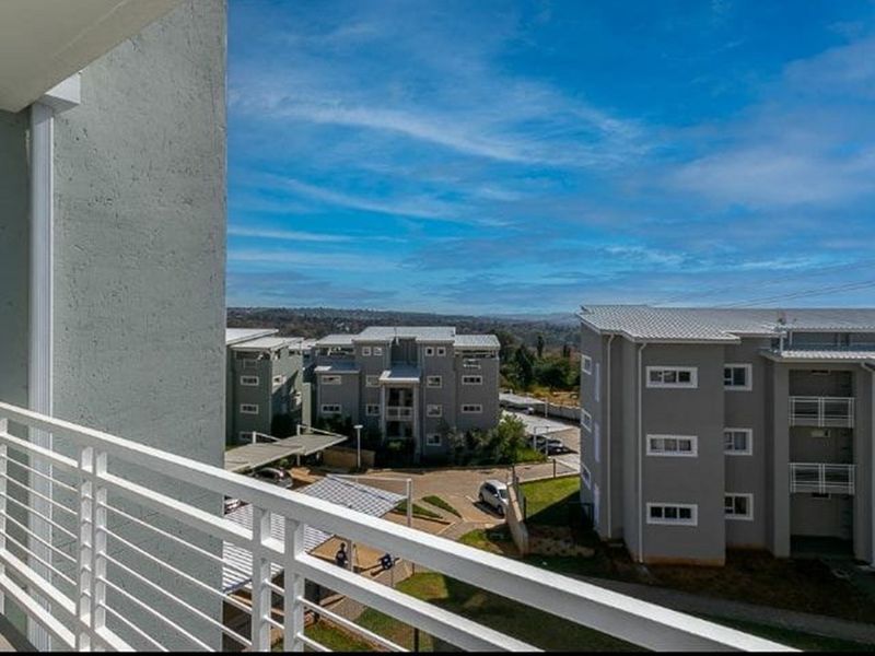 Elevated view from a balcony overlooking the apartment complex grounds and surrounding landscape.