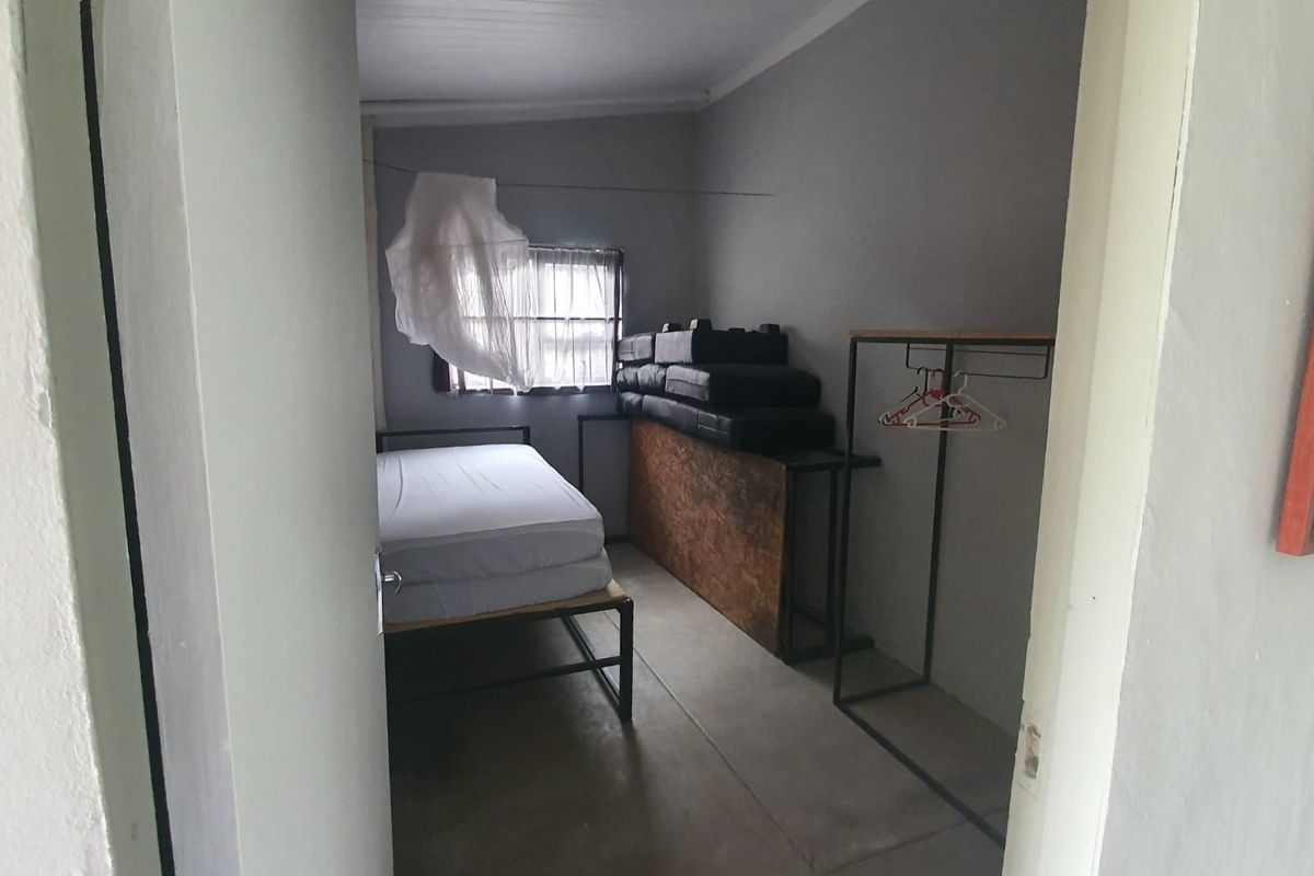 A compact bedroom featuring a simple layout with a window, painted walls, and basic flooring, suitable for a guest room or study.