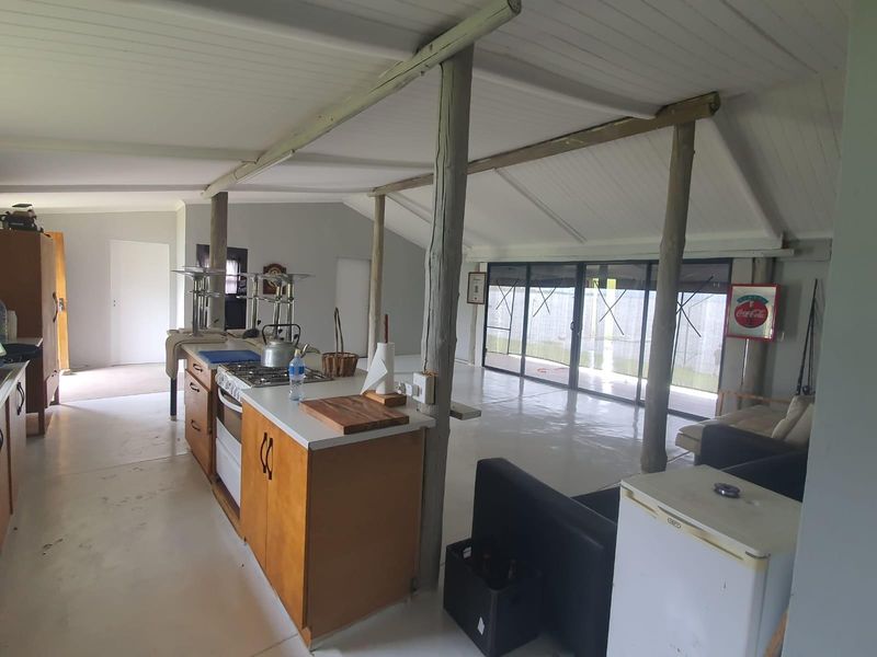 Open-plan living area featuring a functional kitchen with built-in stove, timber structural posts, and large sliding glass doors leading to the exterior.