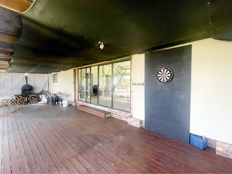 Covered outdoor patio featuring timber decking, a built-in pizza oven, and large sliding glass doors providing access to the interior living space.