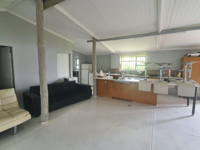 Open plan living and kitchen area featuring exposed timber support posts, a breakfast bar, and a functional kitchen layout with built-in cabinetry.