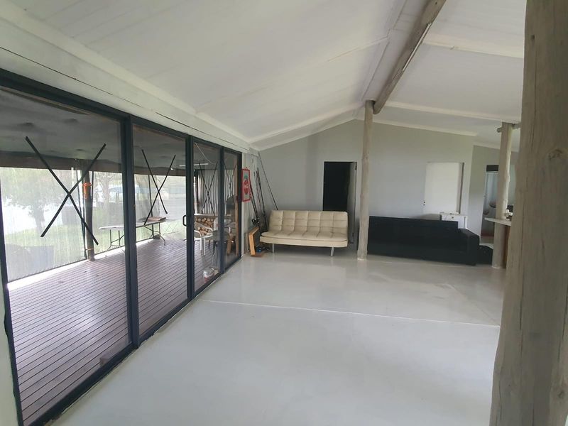 Spacious open-plan living area featuring large sliding glass doors that open onto a covered deck, creating a seamless indoor-outdoor flow.