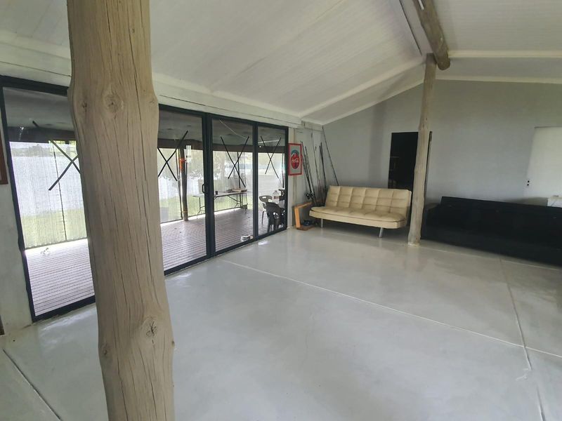 Spacious open-plan living area featuring high vaulted ceilings, polished concrete flooring, and large sliding glass doors opening onto an outdoor deck.
