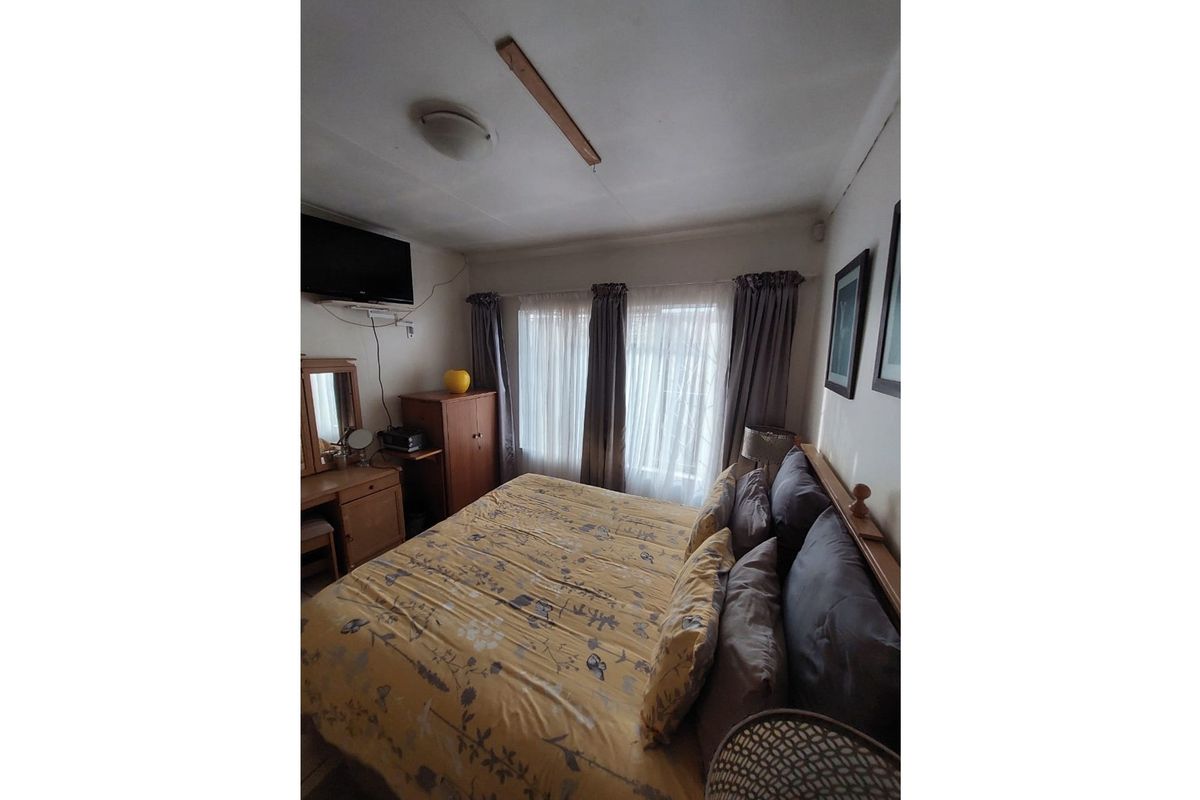 A bedroom featuring a window with curtains and a ceiling-mounted light fixture.