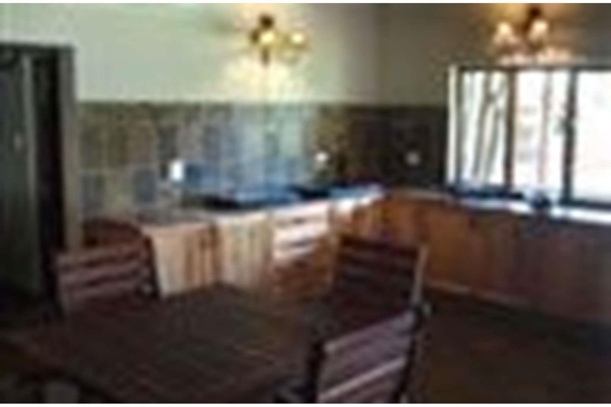 A rustic kitchen featuring wooden cabinetry, tiled backsplash, and integrated cooking surfaces, offering a functional workspace within the farm property.