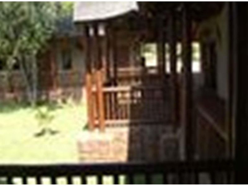 A view of the farm property's exterior, featuring a covered patio area with wooden railings overlooking a garden space.
