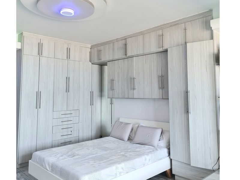 A well-appointed bedroom featuring extensive built-in cabinetry with light wood-grain finish, providing ample integrated storage space around the bed area.