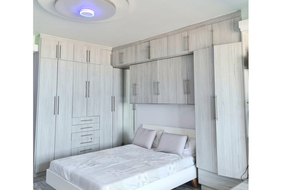 A well-appointed bedroom featuring extensive built-in cabinetry with light wood-grain finish, providing ample integrated storage space around the bed area.